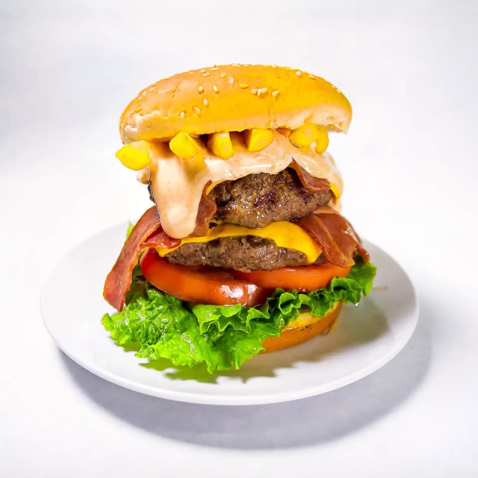 Quickie’s double cheeseburger with bacon, fries, lettuce, tomato, and special sauce on a white plate.