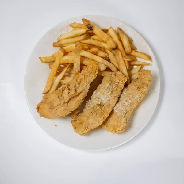 A white plate holds three crispy fried fish fillets and a pile of golden french fries.