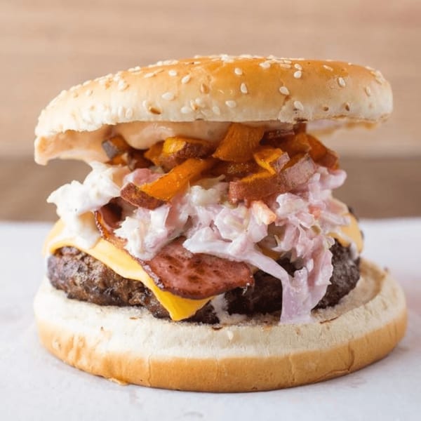A Quickie’s burger with a thick patty, melted cheese, bacon, coleslaw, and sweet potato fries.