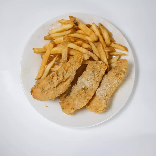 A white plate holds three pieces of fried fish and a pile of golden french fries.
