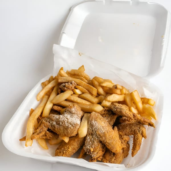 Quickie's fried chicken wings and french fries in a white takeout container.