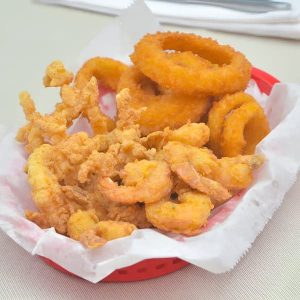 A red basket filled with golden-brown fried shrimp, clams, and onion rings from Quickie’s.
