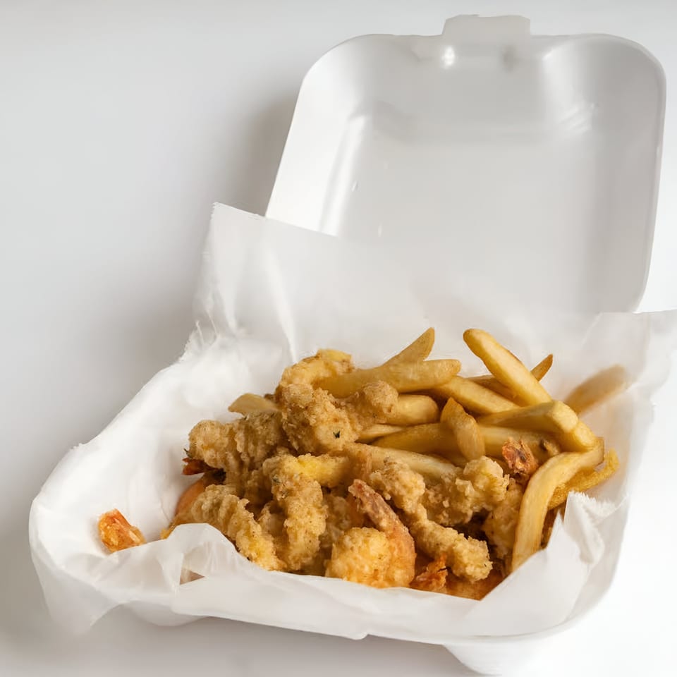 Quickie's fried shrimp and french fries in a white takeout container with a paper liner.